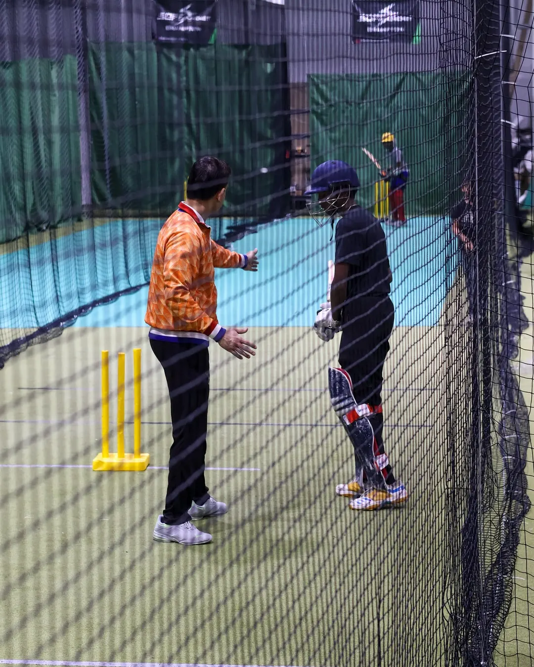 A coach working with a player in the nets at a SOFF indoor facility